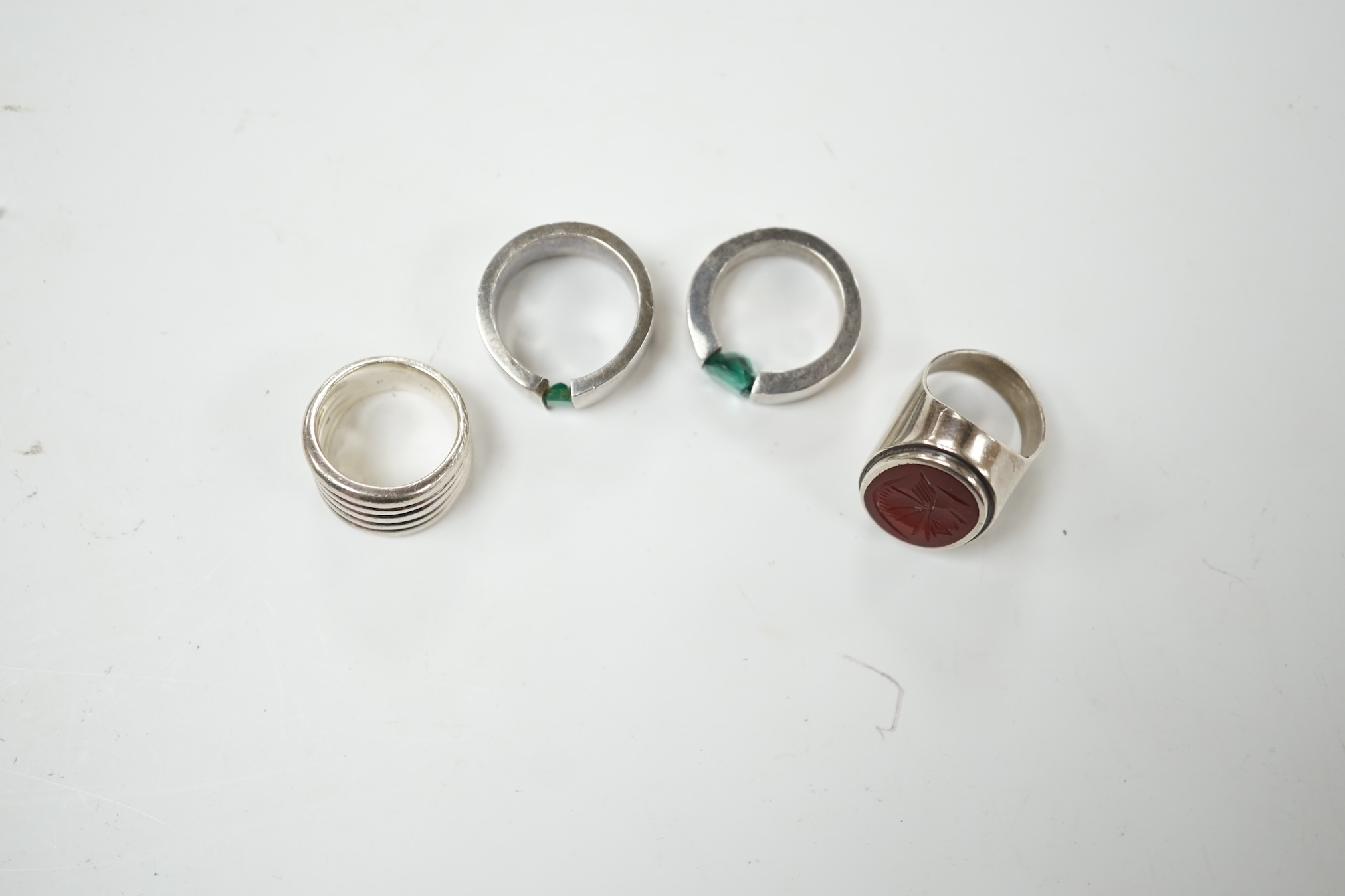 Two modern silver rings, one with coiled shank, the other set with intaglio carnelian and two other white metal rings, one set wit an emerald, the other green quartz, maker's mark P&T. Condition - fair